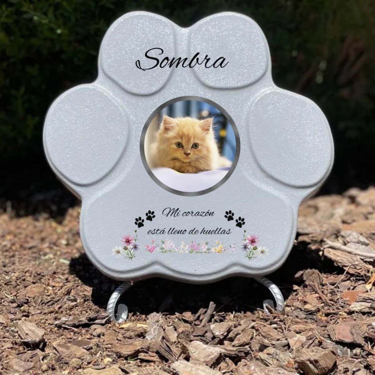 Lápida con forma de huella de piedra personalizada en gris tamaño mediano, con soporte. Incluye ejemplo con la foto de tu gato, su nombre y un Mensaje. Un recuerdo único y emotivo para honrar su memoria.

