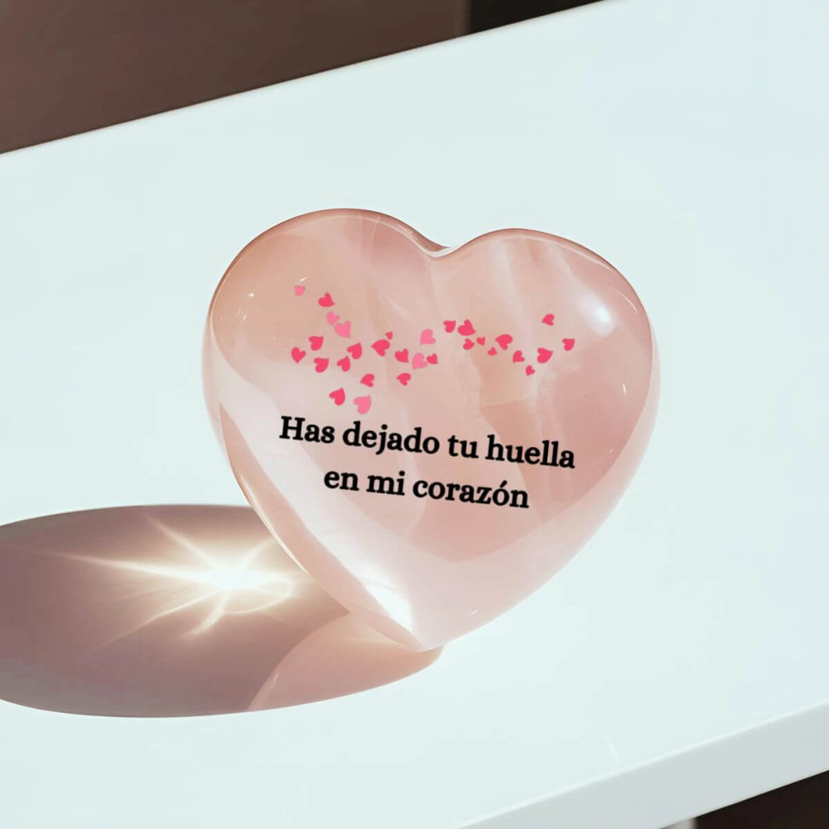 Parte trasera del corazón de cuarzo rosa personalizado con la frase “Has dejado tu huella en mi corazón”, rodeada de pequeños corazones rosados.

