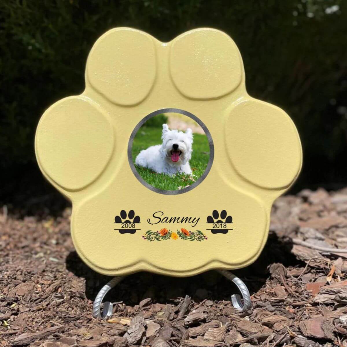 Lápida con forma de huella para mascotas, hecha de piedra amarillo, tamaño mediano con soporte. Personalizada con foto, nombre y fechas importantes del perro o gato. Ejemplo de homenaje conmemorativo único.