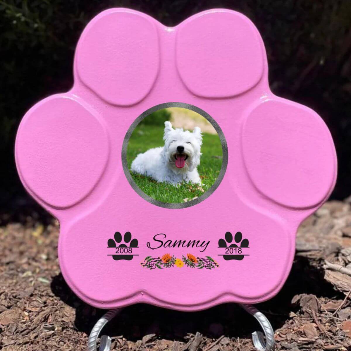Lápida con forma de huella para mascotas, hecha de piedra rosa, tamaño grande con soporte. Personalizada con foto, nombre y fechas importantes del perro o gato. Ejemplo de homenaje conmemorativo único.

