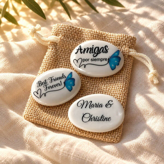 Piedra de amistad personalizada con mariposa azul, mensaje en español o inglés y nombres en el reverso, presentada sobre una bolsita de yute.
