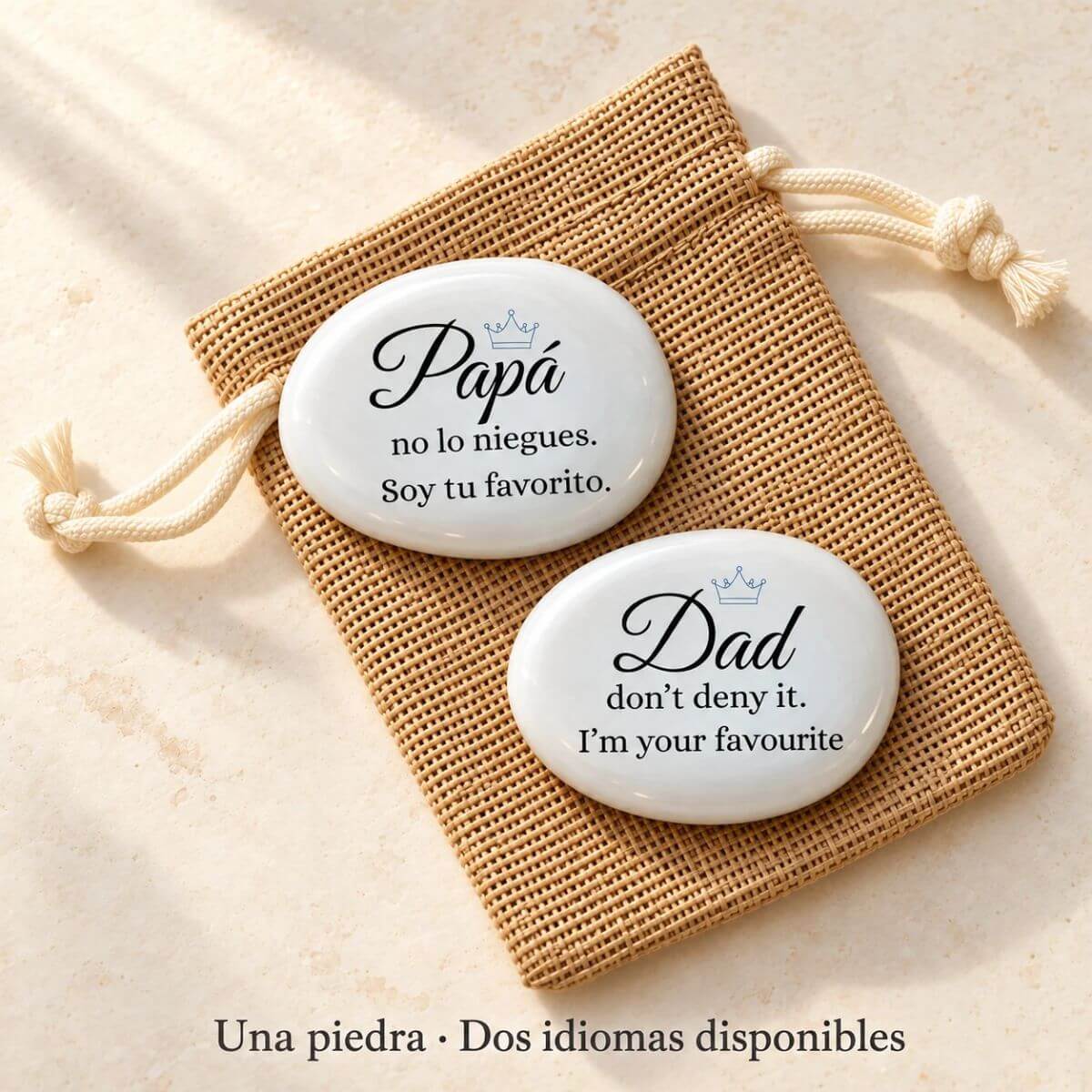 Piedra personalizada para papá con corona azul y mensaje «Soy tu favorito» o «I’m your favourite», mostrando las opciones en español e inglés sobre una bolsita de yute.