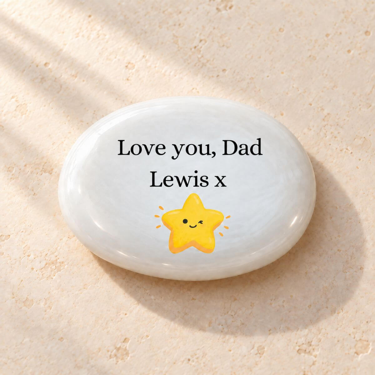 Reverso de piedra personalizada para papá en inglés con «Love you, Dad», el nombre Lewis seguido de un beso «x» y una estrella amarilla sonriente sobre cristal blanco perlado.